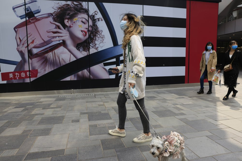 A woman walks her dog in a retail district in Beijing on Thursday, April 15, 2021.