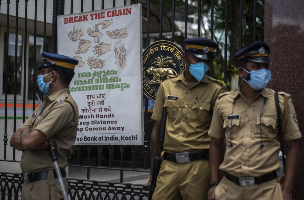 Police personnel wearing masks guard outside the Reserve Bank of India during a protest against the federal government's plan to privatize government assets in Kochi, Kerala state, India, Tuesday, Aug.31, 2021.