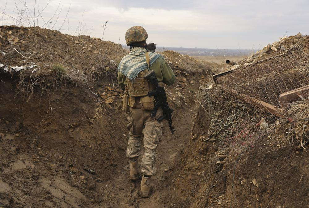 A Ukrainian soldier holds a cat and walks in a trench on the line of separation from pro-Russian rebels near Debaltsevo, Donetsk region, Ukraine, Ukraine Friday, Dec 3, 2021.