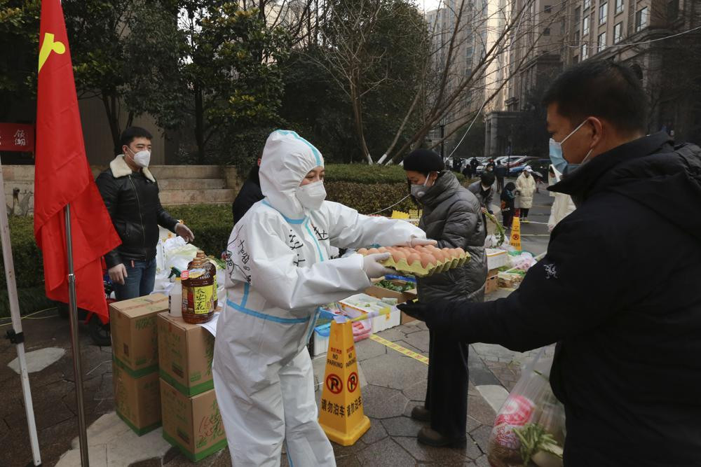 A community volunteer hands over eggs to a buyer at a temporary food store to provide supplies to residents outside a residential block in Xi'an city in northwest China's Shaanxi province Monday, Jan. 03, 2022.