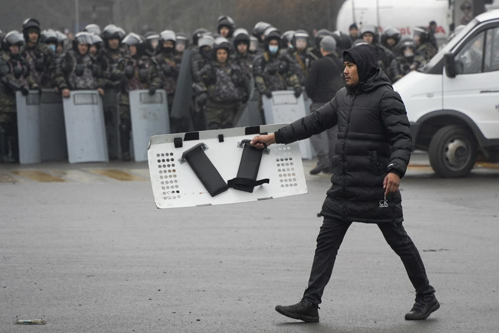 A demonstrator carries a police shield in front of police line during a protest in Almaty, Kazakhstan, Wednesday, Jan. 5, 2022.