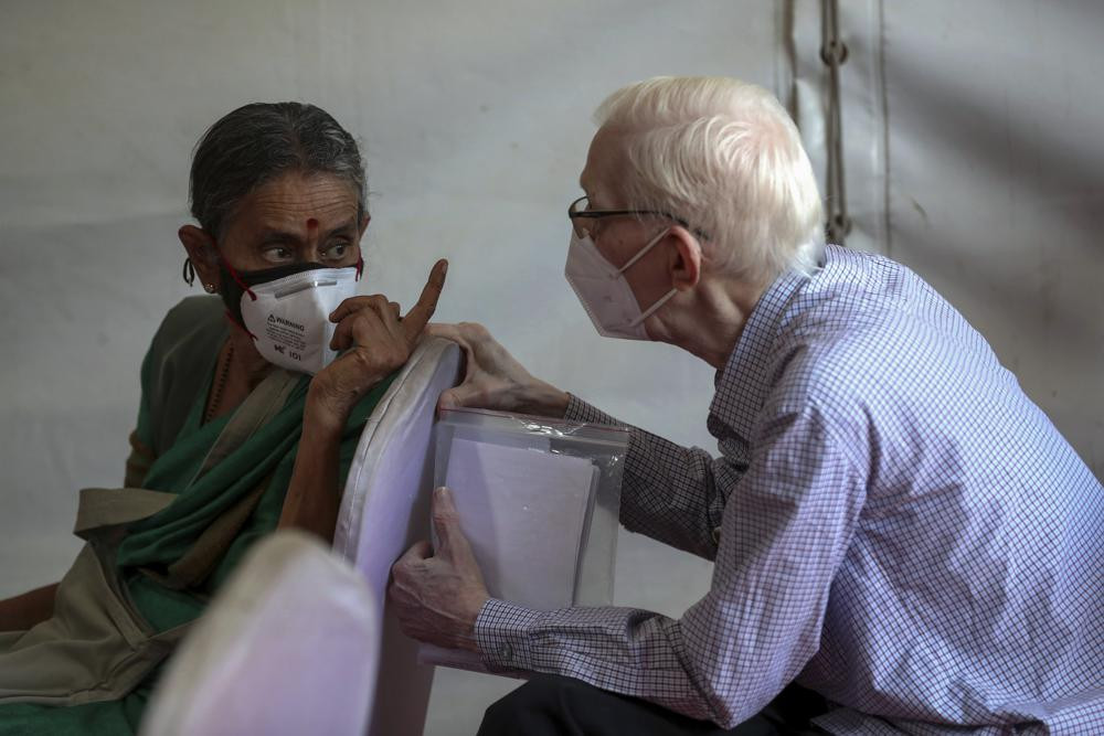 Elderly people chat as they wait to receive the third dose of COVID-19 vaccine at a vaccination center in Bengaluru, India, Monday, Jan. 10, 2022.