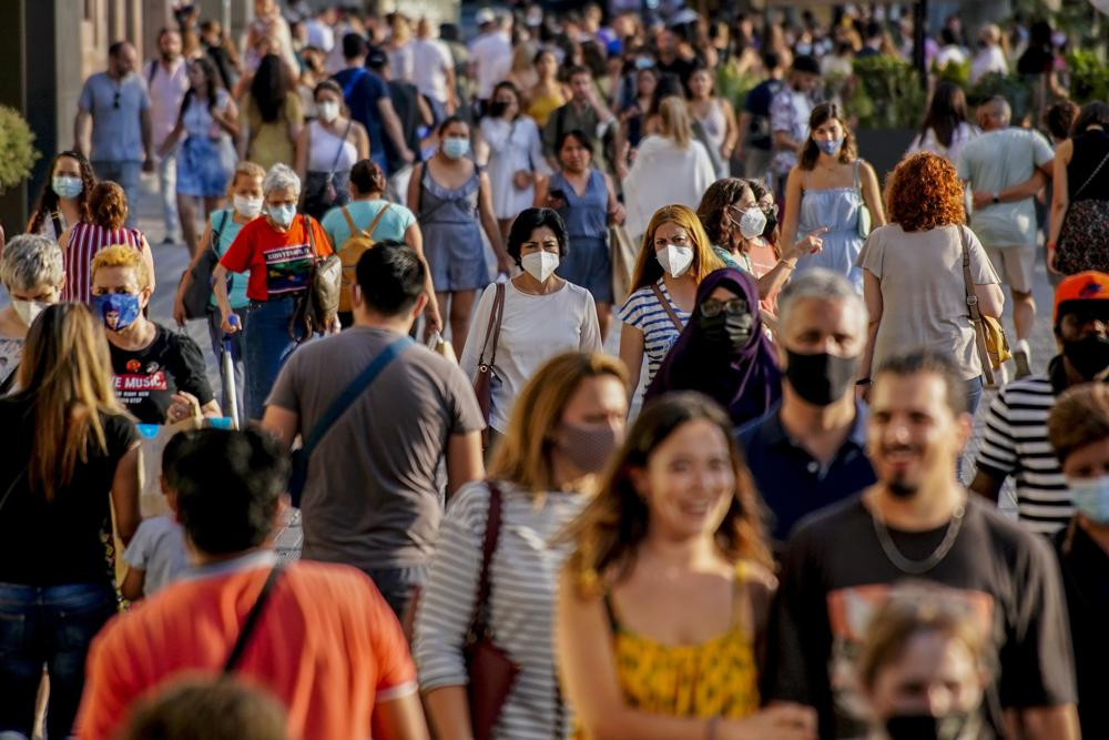 People wearing a face mask to protect against the spread of coronavirus walk along a street in downtown Barcelona, Spain, July 3, 2021.