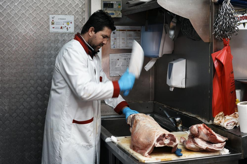 A butcher cuts halal meat in a butcher shop, in Paris, Wednesday, April 13, 2022. Far-right presidential candidate Marine Le Pen is alarming both Muslims and Jews in France with a pledge to ban the ritual slaughter of animals if elected.