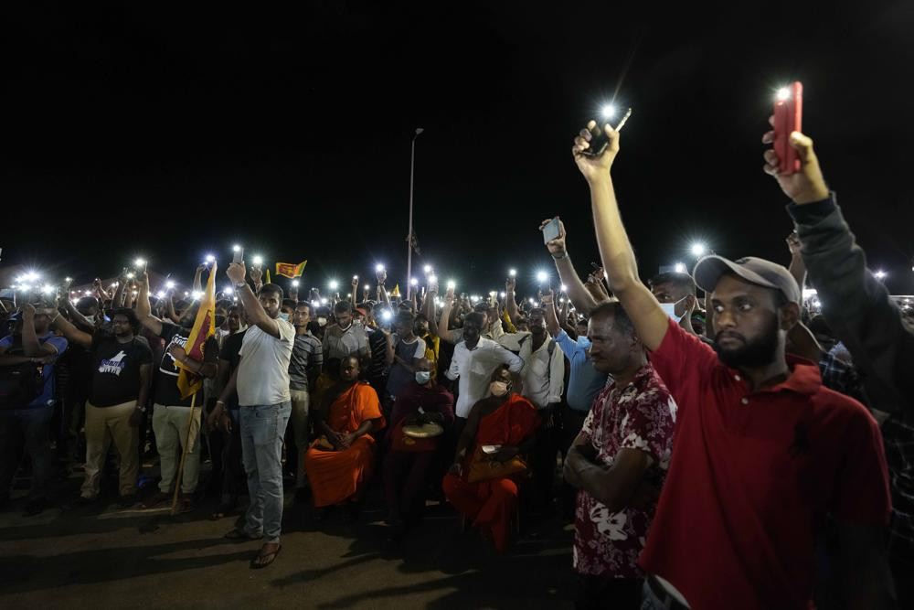 Sri Lankans hold up their mobile phone torches during a vigil condemning police shooting at protesters in Rambukkana, 90 kilometers (55 miles) northeast of Colombo, at a protest outside the president's office in Colombo, Sri Lanka, Tuesday, April 19,