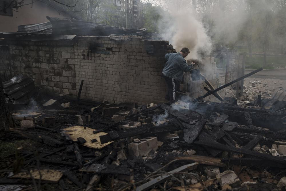 A man tries to extinguish a fire following a Russian bombardment at a residential neighborhood in Kharkiv, Ukraine, Tuesday, April 19, 2022.