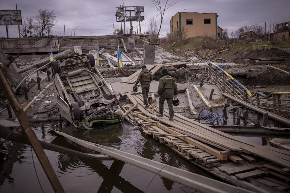 Ukrainian soldiers walk on a destroyed bridge in Irpin, on the outskirts of Kyiv, on Wednesday, April 20, 2022.