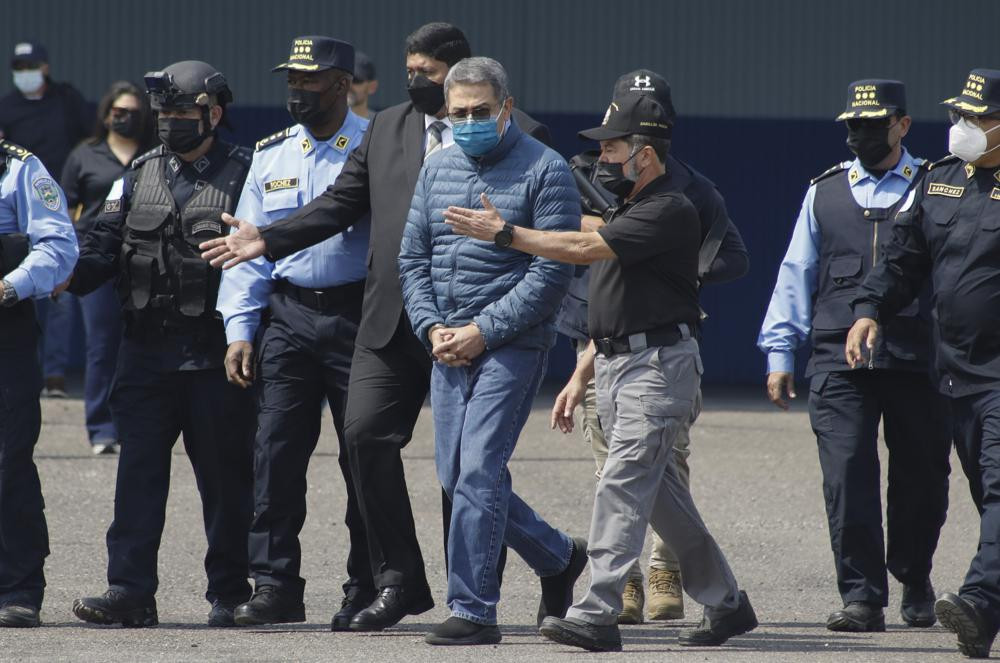 Former Honduran President Juan Orlando Hernandez, center, is taken in handcuffs to a waiting aircraft as he is extradited to the United States, at an Air Force base in Tegucigalpa, Honduras, Thursday, April 21, 2022.