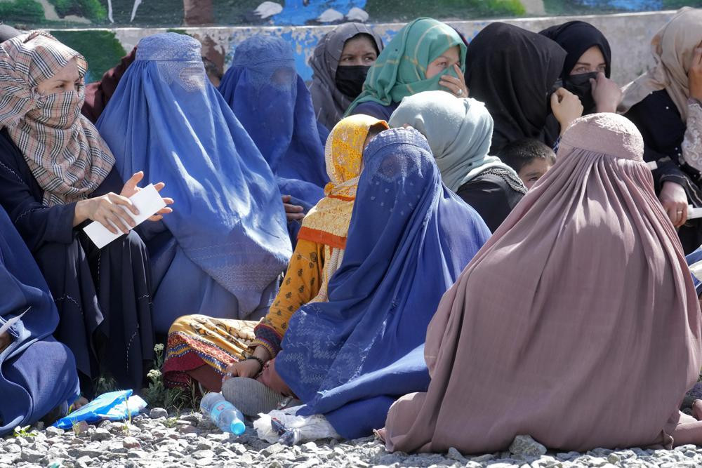 Afghan women wait to receive food rations distributed by a Saudi humanitarian aid group, in Kabul, Afghanistan, Monday, April 25, 2022.