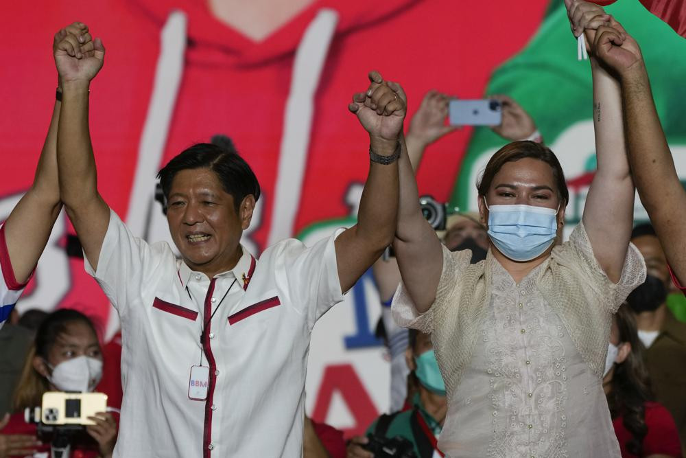 Presidential candidate, Ferdinand Marcos Jr., the son of the late dictator, left, raises arms with running mate Davao City Mayor Sara Duterte, the daughter of the current President, during their last campaign rally Saturday, May 7.