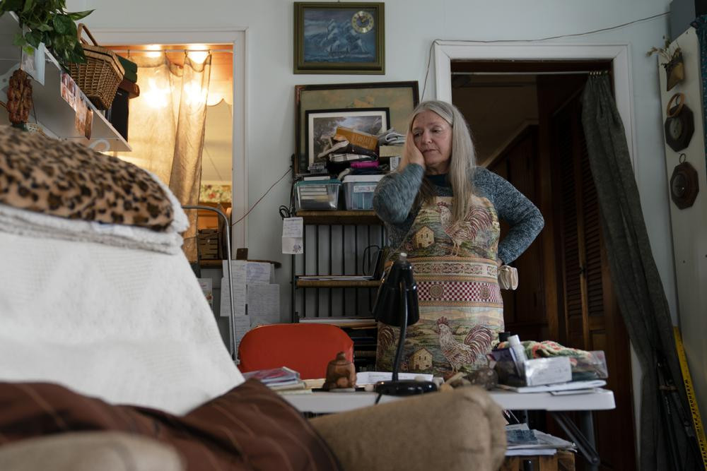 Nancy Rose, who contracted COVID-19 in 2021 and continues to exhibit long-haul symptoms including brain fog and memory difficulties, pauses while organizing her desk space, Tuesday, Jan. 25, 2022, in Port Jefferson, New York.