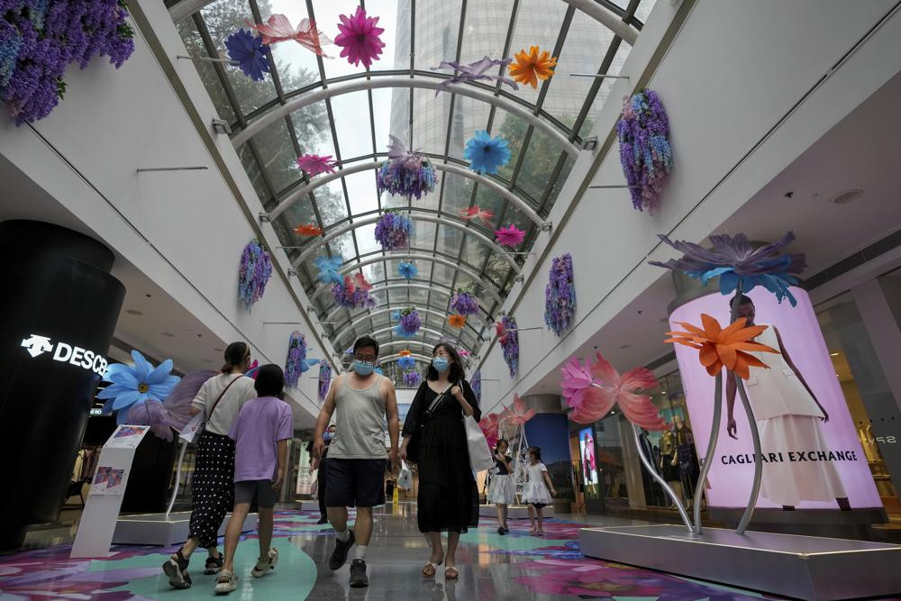 Residents wearing face masks walk through the reopening shopping mall decorated with colorful flowers after being closed due to COVID-19 restrictions in Beijing, Sunday, May 29, 2022.