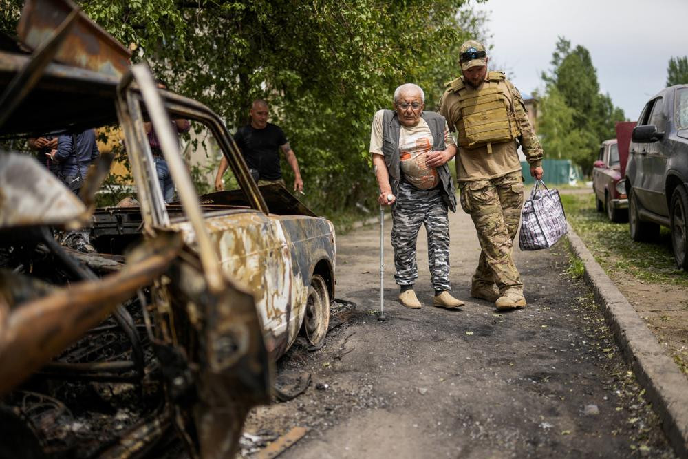 A volunteer helps a man leaving his home in a building damaged by an overnight missile strike, in Sloviansk, Ukraine, Tuesday, May 31, 2022.