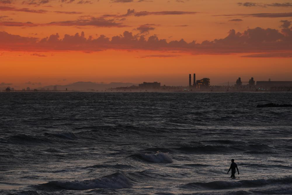 FILE - A man wades into the ocean at sunset on June 22, 2021, in Newport Beach, California.