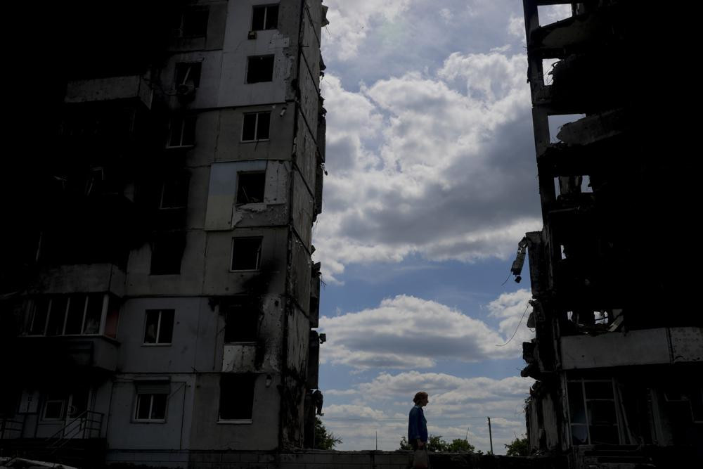 A woman walks in front of buildings destroyed during attacks in Borodyanka, on the outskirts of Kyiv, Ukraine, Saturday, June 4, 2022.