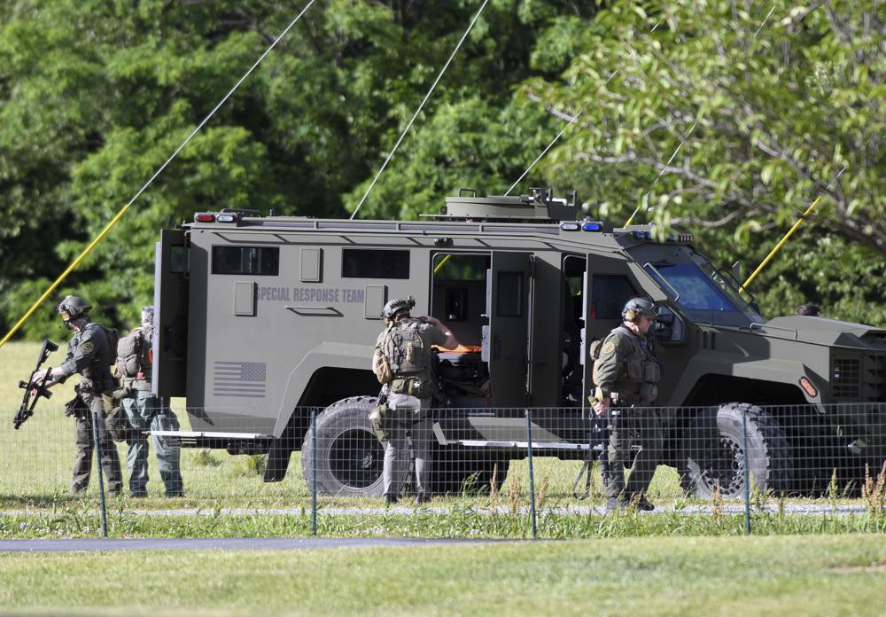 Tactical police work near where a man opened fire at a business, killing three people before the suspect and a state trooper were wounded in a shootout, according to authorities, in Smithsburg, Maryland, Thursday, June 9, 2022.