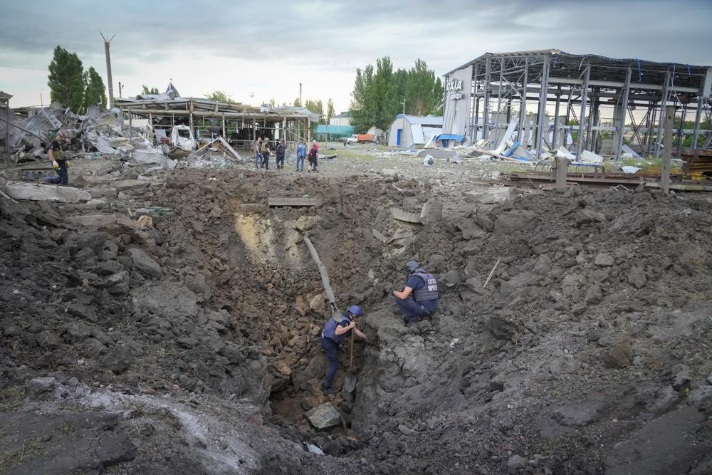 Police members inspect a crater caused by a Russian rocket attack in Pokrovsk, Donetsk region, Ukraine, Wednesday, June 15, 2022.