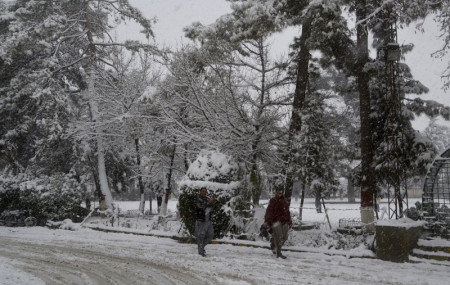 In this Sunday, Jan. 12, 2020, photo, people walk on a road during heavy snow fall in Quetta, capital of Pakistan's southwestern Baluchistan province.