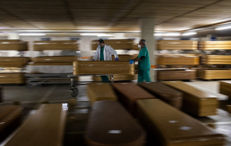 Workers move a coffin with the body of a victim of coronavirus as others coffins are stored waiting for burial or cremation at the Collserola morgue in Barcelona, Spain, Thursday, April 2, 2020.