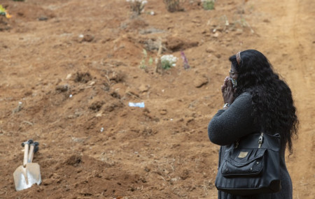 Vera Lucia Souza stands before at the gravesite of her 47-year-old brother Paulo Roberto da Silva, who died of COVID-19, during his burial at the Sao Luiz cemetery in Sao Paulo, Brazil, Thursday, June 4, 2020.