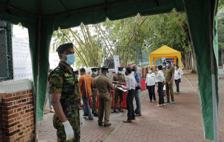 A Sri Lankan government soldier stands guard at the entrance to a ballot counting center as workers show their identity to police officers, a day after voting for general elections in Colombo, Sri Lanka, Thursday, Aug. 6, 2020.