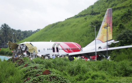 Officials stand on the debris of the Air India Express flight that skidded off a runway while landing in Kozhikode, Kerala state, India, Saturday, Aug. 8, 2020.