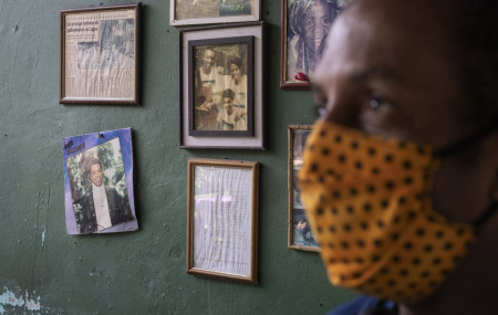 Marcio Antonio do Nascimento stands next to a framed childhood image of his 25-year-old son Hugo do Nascimento who died from the new coronavirus, in Rio de Janeiro, Brazil, Saturday, Aug. 1, 2020.