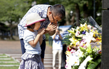 A man and his daughter pray for the victims of U.S. atomic bombing at the Atomic Bomb Hypocenter Park in Nagasaki, southern Japan, Sunday, Aug. 9, 2020.