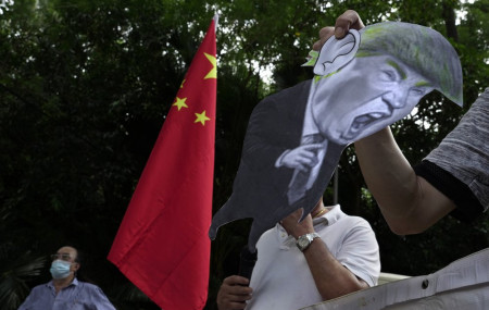 In this Aug. 8, 2020, file photo, pro-China supporters display a picture of U.S. President Donald Trump during a protest against the U.S. sanctions outside the U.S. Consulate in Hong Kong.