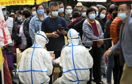 In this photo released by Xinhua News Agency, residents wearing face masks to help curb the spread of the coronavirus line up for the COVID-19 test near the residential area in Qingdao in east China's Shandong province on Tuesday.