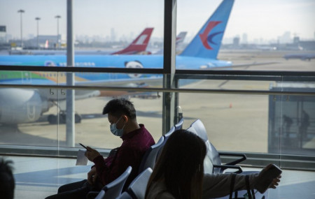 Travelers wearing face masks to protect against the coronavirus sit at a boarding gate at the Shanghai Hongqiao International Airport in Shanghai, Friday, Nov. 6, 2020.