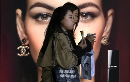 In this Oct. 19, 2020, file photo, women eating snack walk by a Chanel cosmetic shop at the capital city's popular shopping mall in Beijing.
