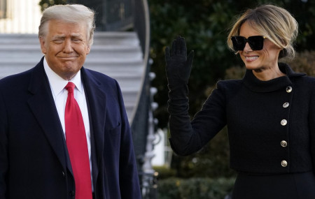US President Donald Trump and first lady Melania Trump stop to talk with the media as they walk to board Marine One on the South Lawn of the White House, Wednesday, Jan. 20, 2021, in Washington.