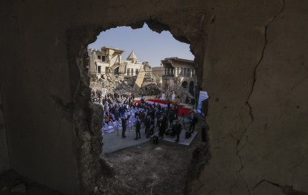 Surrounded by shells of destroyed buildings people arrive to join Pope Francis who will pray for the victims of war at Hosh al-Bieaa Church Square, in Mosul, Iraq, once the de-facto capital of IS, Sunday, March 7, 2021.