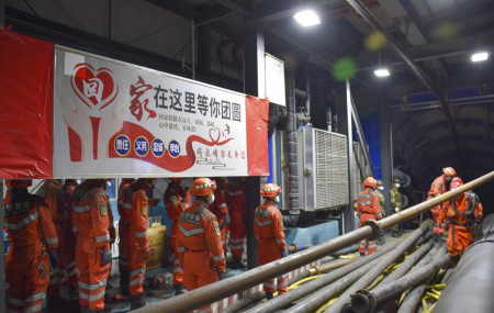 In this photo released by Xinhua News Agency, rescue workers stand near a banner which reads:
