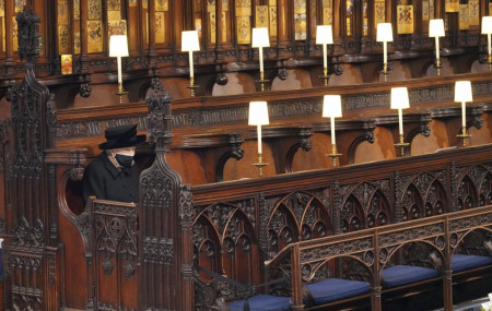 Britain's Queen Elizabeth II sits alone in St. George’s Chapel during the funeral of Prince Philip, the man who had been by her side for 73 years, at Windsor Castle, Windsor, England, Saturday April 17, 2021.