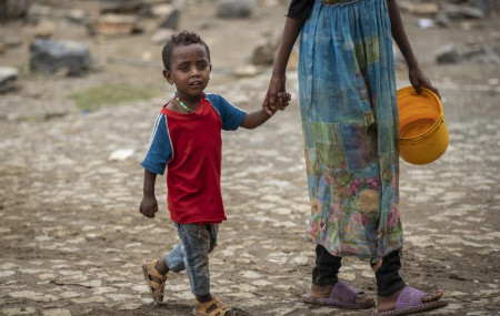 A displaced Tigrayan boy walks with a relative to receive food at the Hadnet General Secondary School which has become a makeshift home to thousands displaced by the conflict, in Mekele, in the Tigray region of northern Ethiopia Wednesday.
