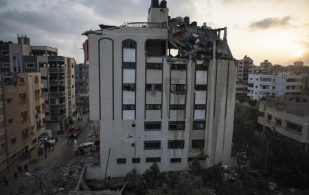 Palestinians search for survivors under the rubble of a destroyed rooftop of a residential building which was hit by Israeli missile strikes, at the Shati refugee camp in Gaza City, early Tuesday, May. 11, 2021.
