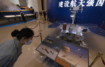 A visitor to an exhibition on China's space program looks at a life size model of the Chinese Mars rover Zhurong, named after the Chinese god of fire, at the National Museum in Beijing on Thursday, May 6, 2021.