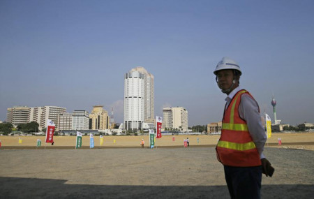 In this Jan. 2, 2018, file photo, a Chinese construction worker stands on land that was reclaimed from the Indian Ocean for the Colombo Port City project, initiated as part of China's ambitious One Belt One Road initiative, in Colombo.