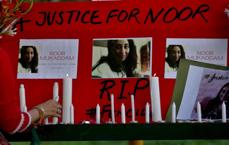 A women's rights activist places a candle beside a poster with the pictures of Noor Mukadam, who was recently beheaded, during a candle light vigil to pay tribute to Noor and other domestic violence victims, in Islamabad.