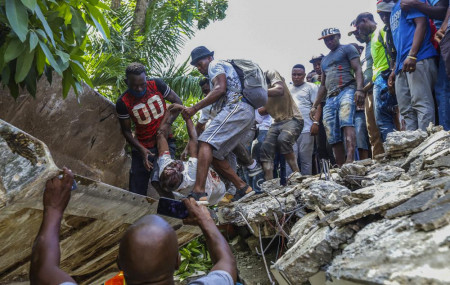 People recover the body of Jean Gabriel Fortune, a longtime lawmaker and former mayor of Les Cayes, from the rubble of the Hotel Le Manguier destroyed by the earthquake in Les Cayes, Haiti, Saturday, Aug. 14, 2021.
