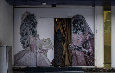 An Afghan woman enters a beauty salon in Kabul, Afghanistan, Saturday, Sept. 11, 2021. Since the Taliban gained control of Kabul, several images depicting women outside beauty salons have been removed or covered up.