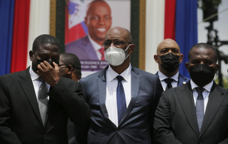 In this July 20, 2021 file photo, Haiti's designated Prime Minister Ariel Henry, center, and interim Prime Minister Claude Joseph, right, pose for a group photo with other authorities in front of a portrait of slain Haitian President Jovenel Moise.