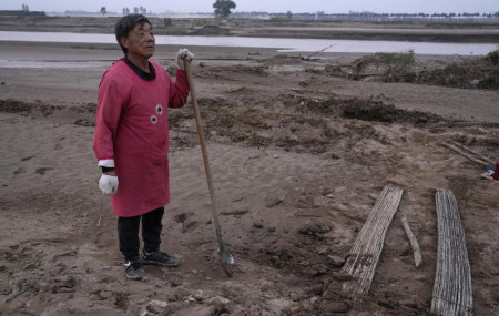 Wang Yuetang stands near what used to be his peanut farm before torrential rains submerged the lowland leaving him with no summer harvest near Xubao village in central China's Henan province on Friday, Oct. 22, 2021.