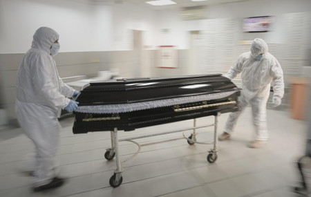 Funeral house employees drag a coffin on a trolley as they arrive at the University Emergency Hospital morgue to take a COVID-19 victim for burial, in Bucharest, Romania, Monday, Nov. 8, 2021.