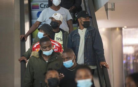 People wearing masks on an escalator at a shopping mall, in Johannesburg, South Africa, Friday Nov. 26, 2021.