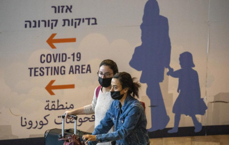 Travelers wearing protective face masks arrive at Ben Gurion Airport near Tel Aviv, Israel, Sunday, Nov. 28, 2021.
