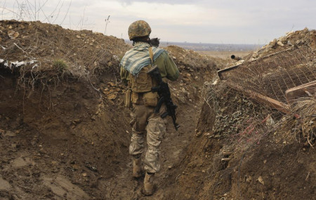 A Ukrainian soldier holds a cat and walks in a trench on the line of separation from pro-Russian rebels near Debaltsevo, Donetsk region, Ukraine, Ukraine Friday, Dec 3, 2021.