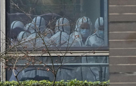 Members of a World Health Organization team are seen through a window wearing protective gear during a field visit to the Hubei Animal Disease Control and Prevention Center in Wuhan on Feb. 2, 2021.